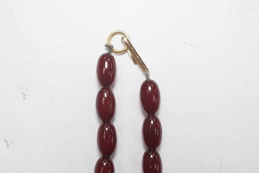 A single strand graduated oval simulated cherry amber necklace, 38cm, gross weight 47 grams. Condition - fair to good